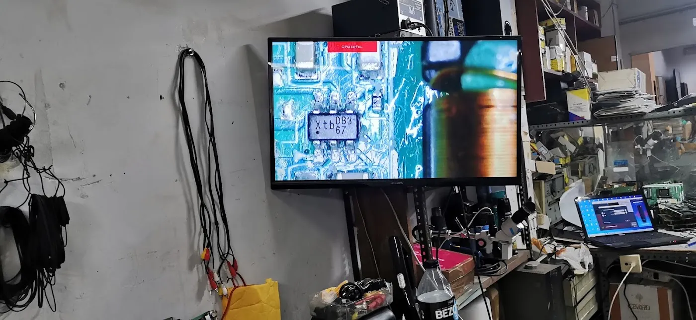 Un televisor reparado, encendido con la carta de ajuste, en la pared del taller